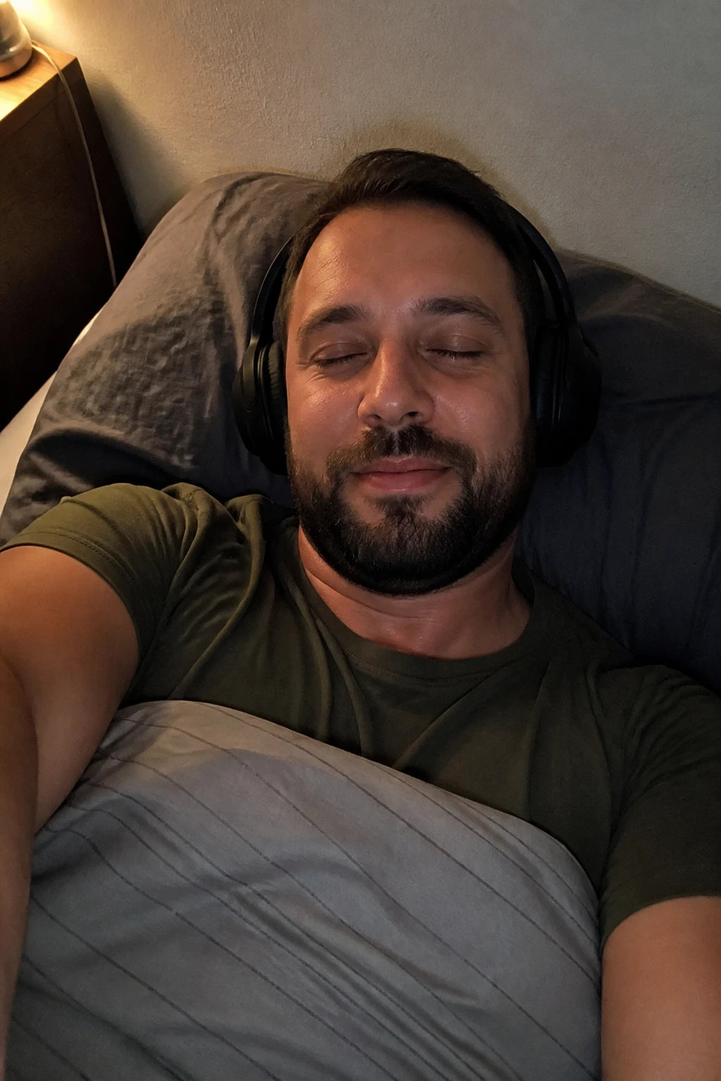 Selfie von Marc mit aufgesetzten Kopfhörern im Bett, Augen zu, entspannt